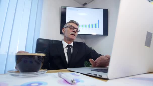 Zakenman drinkt koffie tijdens het kijken naar de laptop scherm — Stockvideo