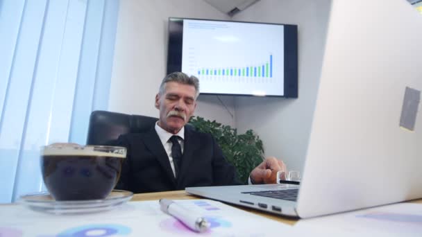 Zakenman drinkt koffie tijdens het kijken naar de laptop scherm — Stockvideo