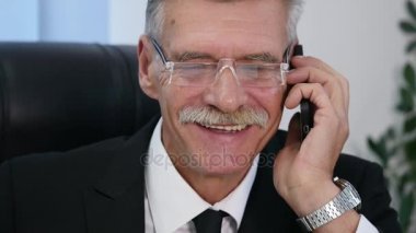 Kıdemli ofis beyaz smartphone ile konuşuyor. yakın çekim