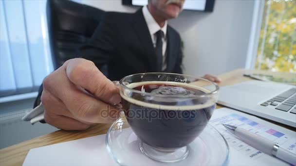 Empresario bebe café mientras mira la pantalla del portátil — Vídeos de Stock