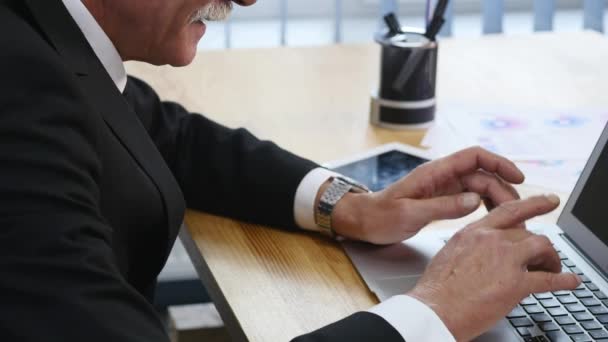 Hombre de negocios de edad avanzada que trabaja con la computadora en la oficina moderna. de cerca — Vídeo de stock