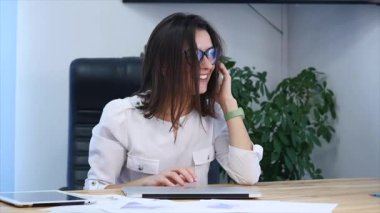 Güzel, başarılı bir kadın modern ofisindeki telefonda konuşuyor