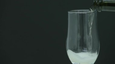 Şampanya kabarcıklar ile bir cam içine siyah arka plan üzerine dökülür.