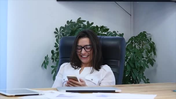 Una hermosa mujer de éxito usando el teléfono en la oficina moderna — Vídeos de Stock