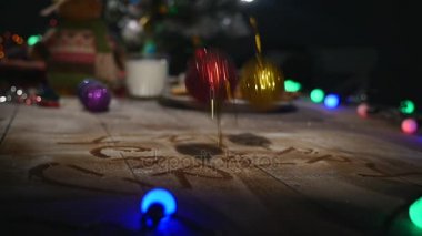 Ahşap kahverengi masa Noel şeyleri ve çelenk ile dekore edilmiştir. Bir bardak süt ve çerezleri Noel masaya bir tabak