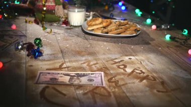 Ahşap kahverengi masa Noel şeyleri ve çelenk ile dekore edilmiştir. Bir bardak süt ve çerezleri Noel masaya bir tabak