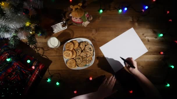 Kerstmis en Nieuwjaar achtergrond. Handen van een man maken notities. Bovenaanzicht. — Stockvideo