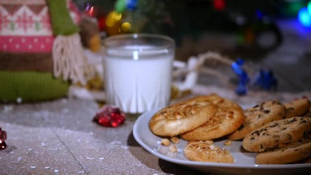 Houten bruine tafel versierd met Kerstmis spullen en slingers. Dames hand zet de cookies op de plaat — Stockvideo