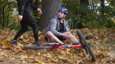 Genç bir kadın bir bisiklet düşmüş bir adam yardımcı olur.