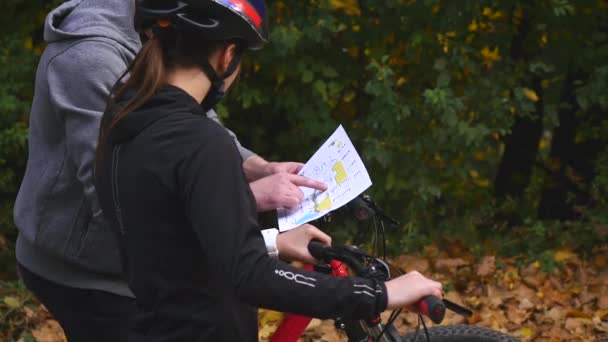 山の自転車に乗るカップル晴れた日にフォレスト内の地図を見て — ストック動画