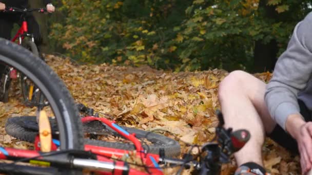 Una joven ayuda a un hombre que se ha caído de una bicicleta — Vídeo de stock