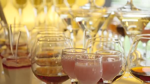 杯子里有酒精和不同的饮料, 酒杯和香槟都在自助餐桌上, 红酒在酒杯里, 香槟在玻璃上, 自助餐桌上有酒在餐厅里, 侧面看 — 图库视频影像