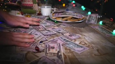 Ahşap kahverengi masa Noel şeyleri ve çelenk ile dekore edilmiştir. Bir bardak süt ve çerezleri Noel masaya bir tabak. Noel masa üzerinde para
