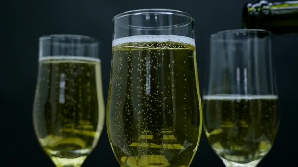 Champagne avec bulles versé dans un verre sur fond noir — Video