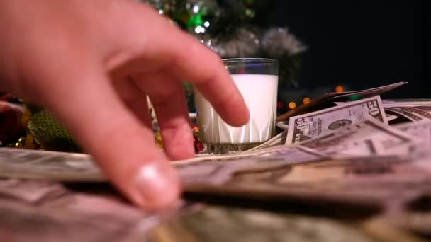 Mesa marrón de madera decorada con cosas navideñas y guirnaldas. Un vaso de leche y un plato de galletas en una mesa de Navidad. dinero en la mesa de Navidad — Vídeos de Stock