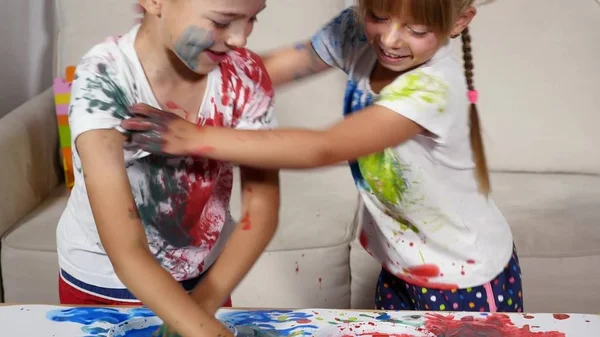 Menina e menino manchar suas camisas na pintura — Fotografia de Stock