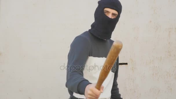 Агрессивный человек в маске с бейсбольной битой — стоковое видео