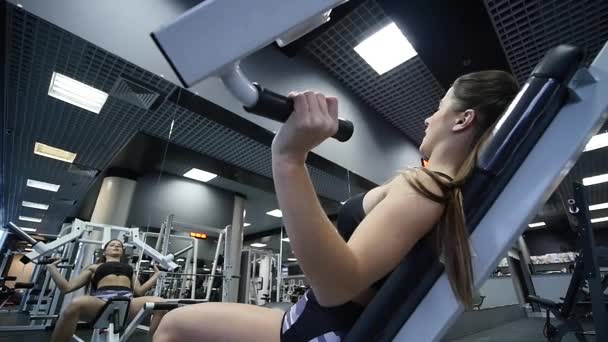 Mujer entrena brazos y hombros en simulador en gimnasio — Vídeo de stock
