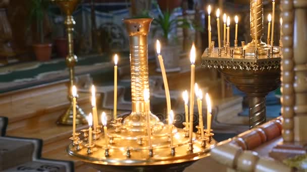 Vista alla Chiesa Dalle candele accese Volto di Cristo nell'icona. Lecca le candele della fiamma santa. Molte candele della Chiesa che bruciano nel tempio del piano a lungo raggio non sono a fuoco Icona nella Chiesa — Video Stock