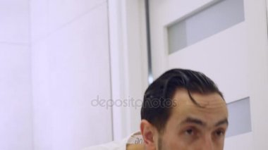 Yakın çekim. Adam aynanın önünde yıkar. Beyaz bir T-shirt yorgun tıraşsız adam