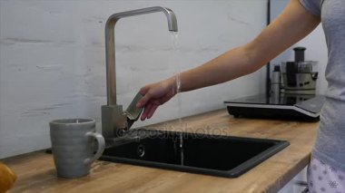 kadın mutfak musluk kullanır, kadının el musluk su mutfakta açar.