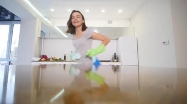 Derin bir yaka ile sıkı bir gri T-shirt bir kadında bir bez ile büyük mutfak masası mendil