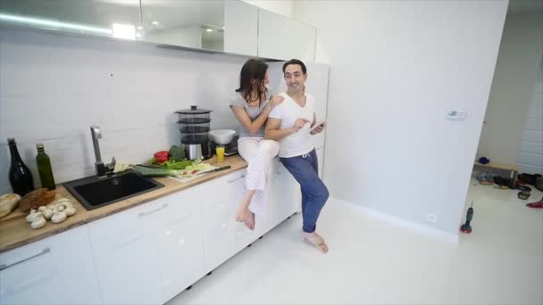 Щаслива пара з планшетним комп'ютером на кухні вдома. повільний рух — стокове відео