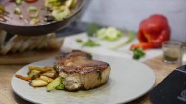 Kadın eti biftek ve sebze bir tabağına koyuyor