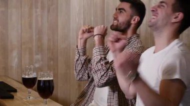 İki genç erkek arkadaş otururken bar ve birbirleri ile bira yudumlarken konuşuyor.