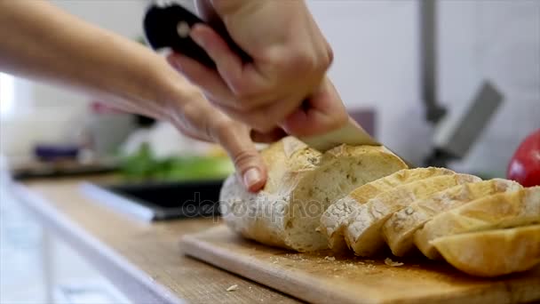 Una mujer cortando una barra de pan con un cuchillo de pan. cámara lenta — Vídeos de Stock