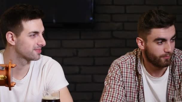 Két fiatal férfi meg ül a bárban, és beszél egymással, miközben ivott sört. — Stock videók