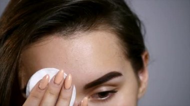 kız temiz ve taze yüzünü yapma. Yüzünü sünger ile silme ve gri arka plan üzerinde izole dururken gülümseyen güzel genç üstsüz kadın. Yakın çekim