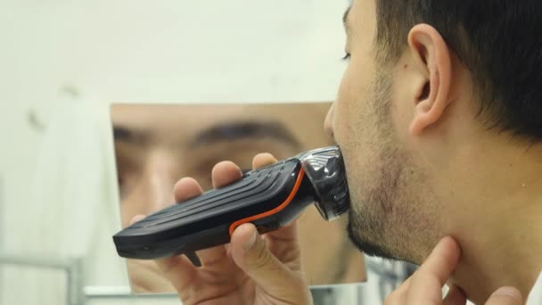 Mladý muž, holení vousů s holicí strojek v koupelně — Stock video