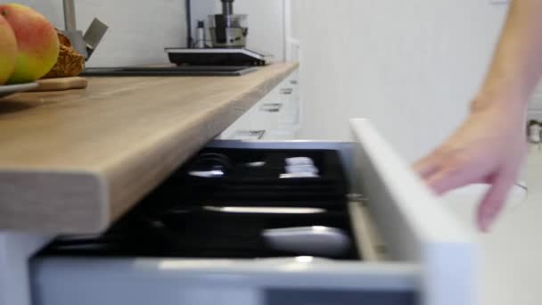 Женщина открывает ящики шкафа на белой кухне — стоковое видео