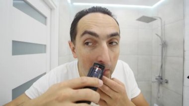 Genç adam banyoda Elektrikli tıraş makinesi ile sakalını tıraş