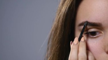 güzel bir genç kadın onun kaş tarak. Güzel kadın kozmetik fırça kullanarak kaşları güzellik şekli çizin. Yakın çekim