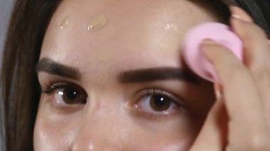 Güzellik kozmetik. Yüzünde ton krem Bankası uygulama Closeup güzel seksi kadın. Makyaj, kozmetik ürün, temel yüz cilt üzerine koyarak çekici genç kadın portresi. Yüksek çözünürlük
