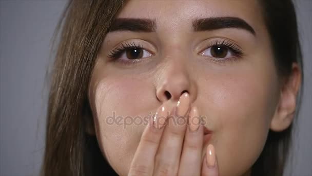 Closeup cabeça de menina morena bonita olhando para a câmera e enviando beijo de ar sobre fundo de parede estúdio cinza — Vídeo de Stock