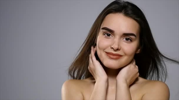 Joven hermosa morena posando en el estudio. Retrato de moda de una mujer hermosa. Mujer alegre con cabello castaño largo aislado sobre fondo gris — Vídeo de stock