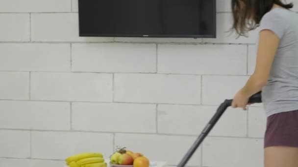 A young girl is cleaning the house using a vacuum cleaner and danced — Stock Video