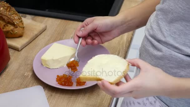 Vrouwelijke handen maken broodjes met rode kaviaar — Stockvideo