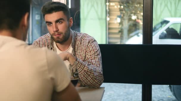 İki genç erkek arkadaş otururken bar ve birbirleri ile bira yudumlarken konuşuyor — Stok video