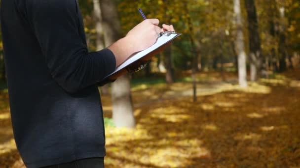 Handsome man writes something by pen on a piece of paper — Stock Video