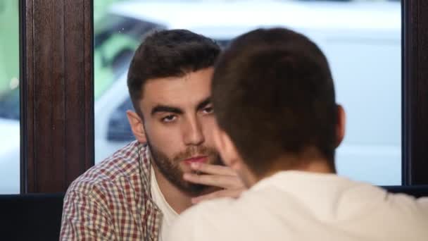 Dos jóvenes amigos sentados en el bar y hablando entre sí mientras beben cerveza . — Vídeo de stock