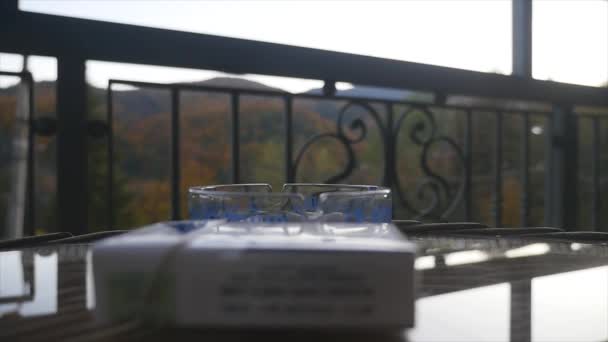 Man putting out a smoking cigarette in a ashtray with mountains in the background — Stock Video