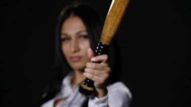 Vahşice kameraya bakarak, yarasa siyah arka plan üzerinde tutan genç güzel kız. ağır çekim