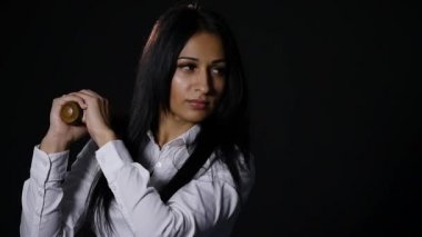 Vahşice kameraya bakarak, yarasa siyah arka plan üzerinde tutan genç güzel kız. ağır çekim