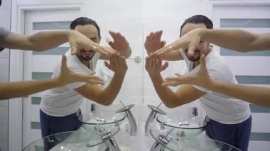 Farklı şekiller bir T-shirt banyoda ayna önünde genç bir adam yapar