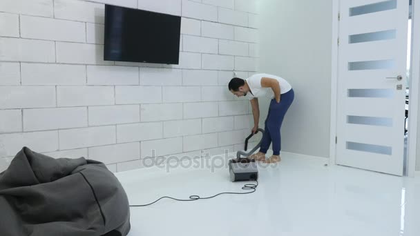 Portret van blije, jonge man reinigen, hoovering zijn nieuwe huis — Stockvideo