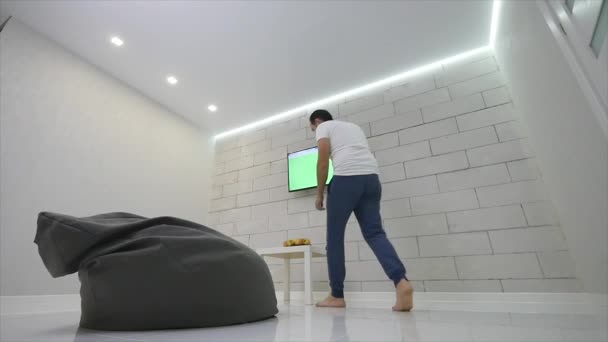 Человек смотрит телевизор с зеленым экраном в комнате — стоковое видео